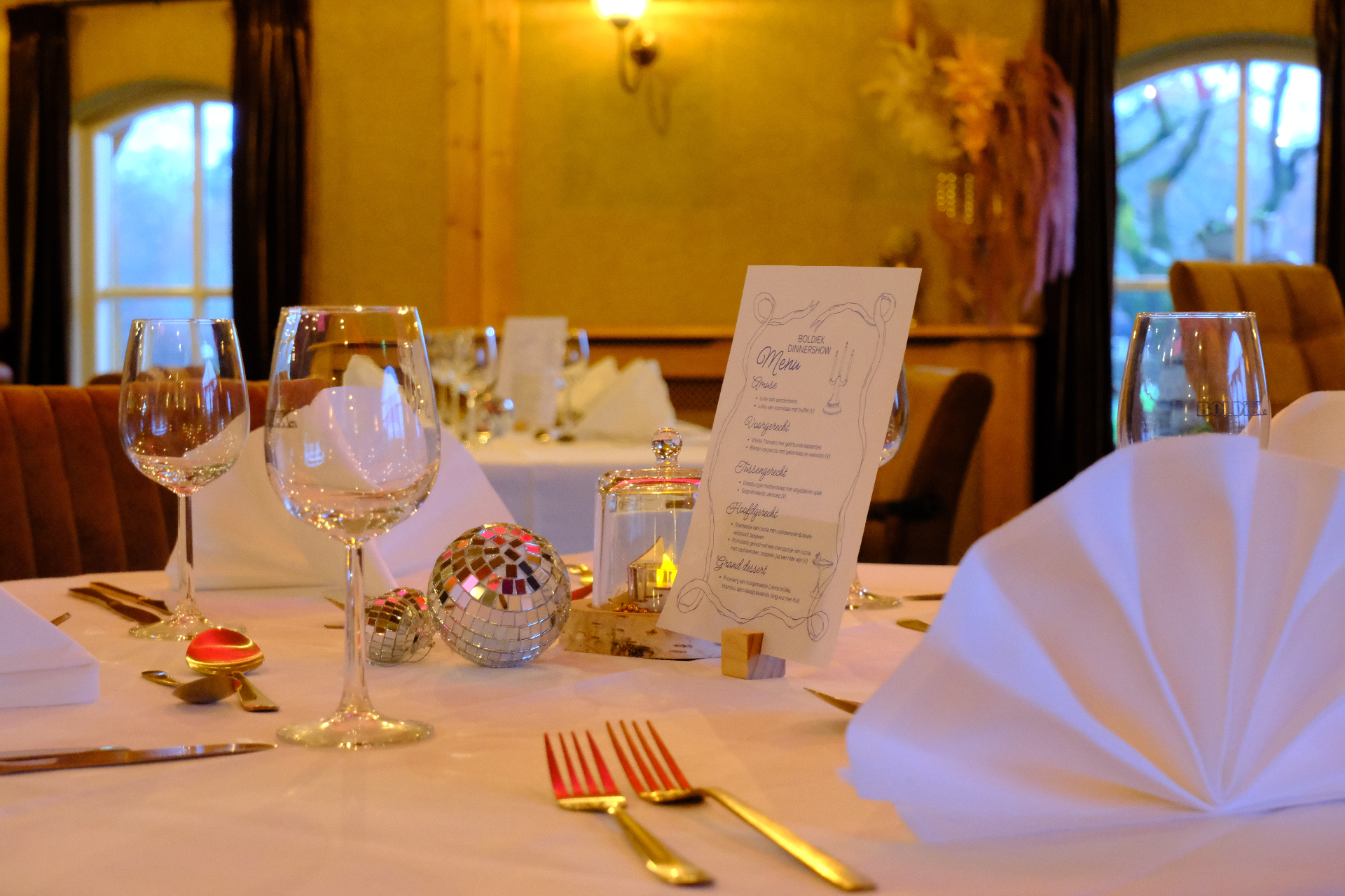 Feestelijk gedekte tafel met menukaart en discoballen tijdens dinershow
