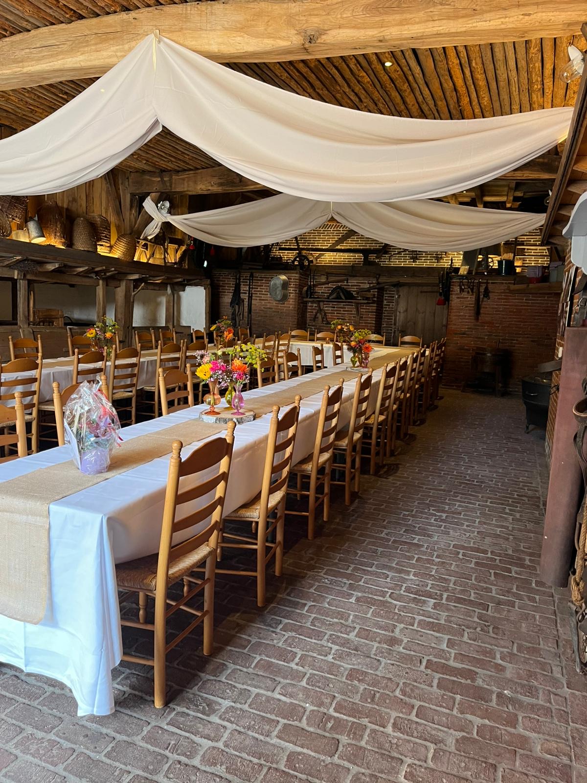 Hofshuus met lange gedekte tafels en witte doeken aan plafond