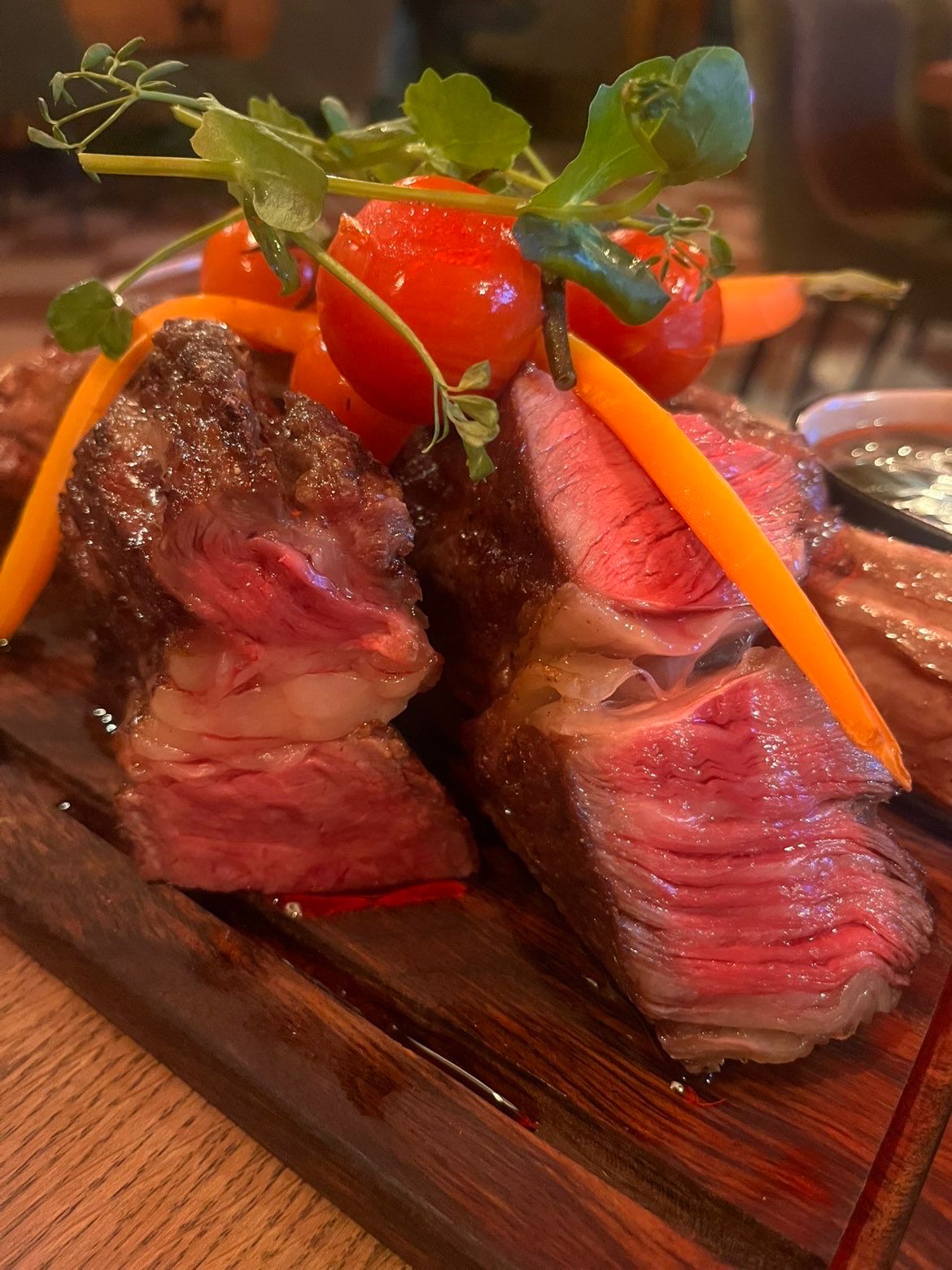 Gegrilde steak rosé gebakken op houten plank met tomaatjes en kruiden